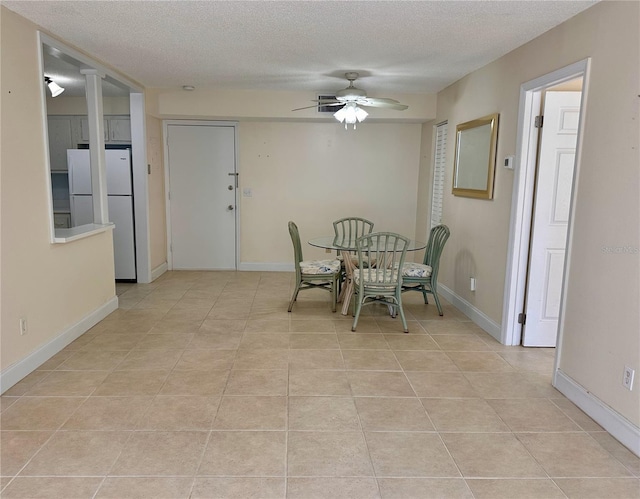 dining area with a textured ceiling, baseboards, and ceiling fan