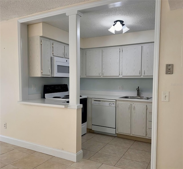 kitchen featuring white appliances, light tile patterned floors, a sink, light countertops, and a textured ceiling