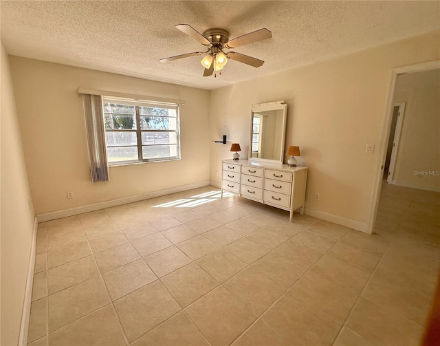 unfurnished bedroom featuring light tile patterned floors, a ceiling fan, baseboards, and a textured ceiling