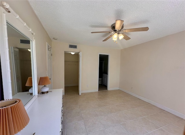 unfurnished bedroom with visible vents, a textured ceiling, a closet, light tile patterned floors, and a spacious closet