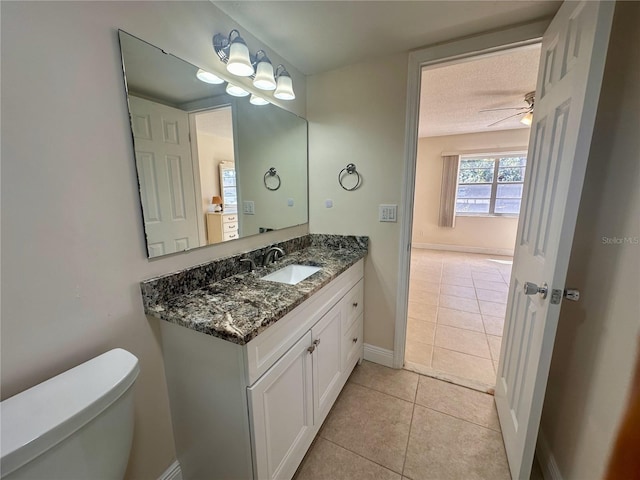 bathroom featuring vanity, baseboards, a textured ceiling, tile patterned floors, and toilet