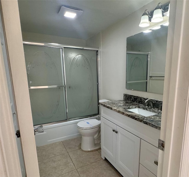 bathroom featuring combined bath / shower with glass door, toilet, vanity, and tile patterned flooring