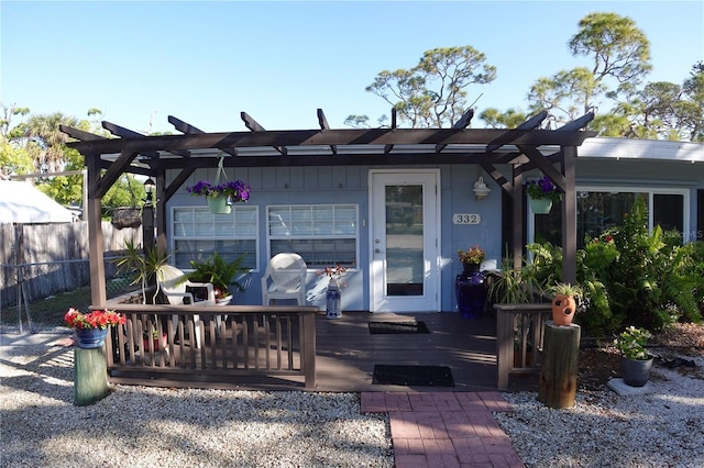 rear view of house with a deck, fence, and a pergola