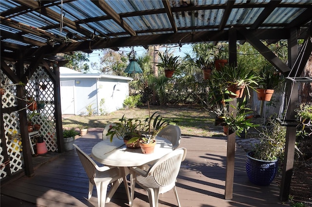 wooden terrace featuring an outbuilding, a storage shed, outdoor dining area, and fence