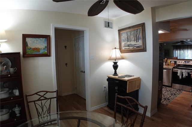 hallway featuring visible vents, baseboards, and wood finished floors