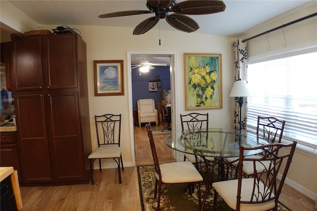 dining room with a wealth of natural light, light wood finished floors, baseboards, and a ceiling fan