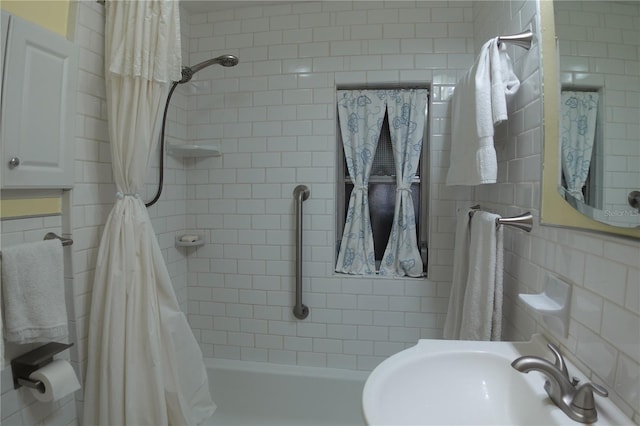 full bath featuring shower / bathtub combination with curtain, tile walls, and a sink