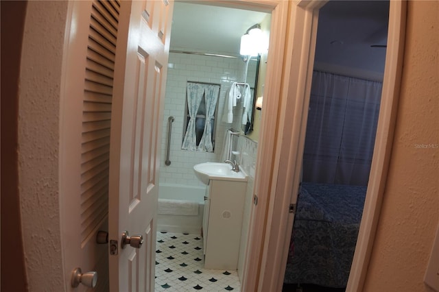 full bathroom featuring tile patterned floors, vanity, a textured wall, and shower / bathtub combination with curtain