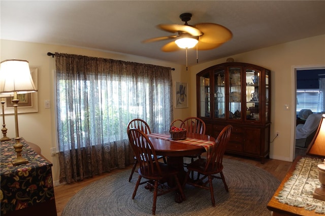 dining area with baseboards, light wood-style floors, and a ceiling fan