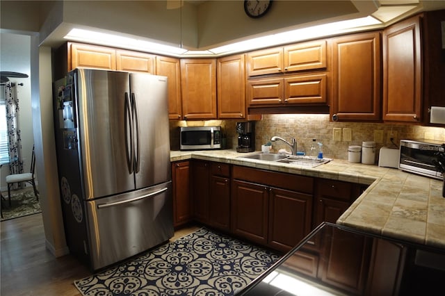 kitchen with tile counters, backsplash, appliances with stainless steel finishes, and a sink