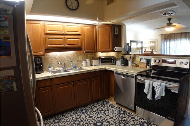 kitchen featuring a sink, tasteful backsplash, stainless steel appliances, a peninsula, and ceiling fan