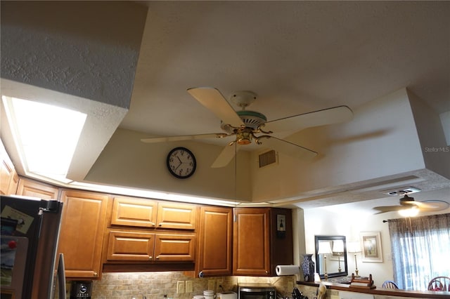 room details featuring tasteful backsplash, visible vents, freestanding refrigerator, and ceiling fan