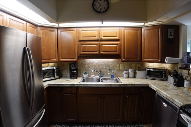 kitchen featuring a sink, appliances with stainless steel finishes, a toaster, decorative backsplash, and tile counters