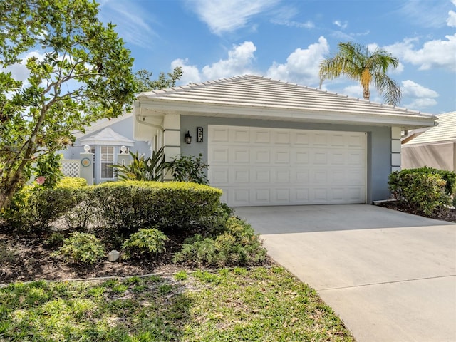 view of front of property with stucco siding, an attached garage, a tile roof, and concrete driveway