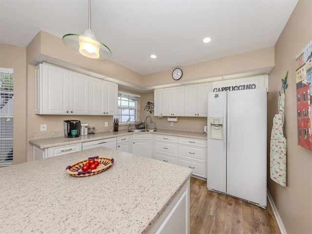 kitchen with white refrigerator with ice dispenser, white cabinets, light wood-style flooring, and a sink