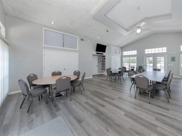 dining room with a ceiling fan, high vaulted ceiling, baseboards, and wood finished floors
