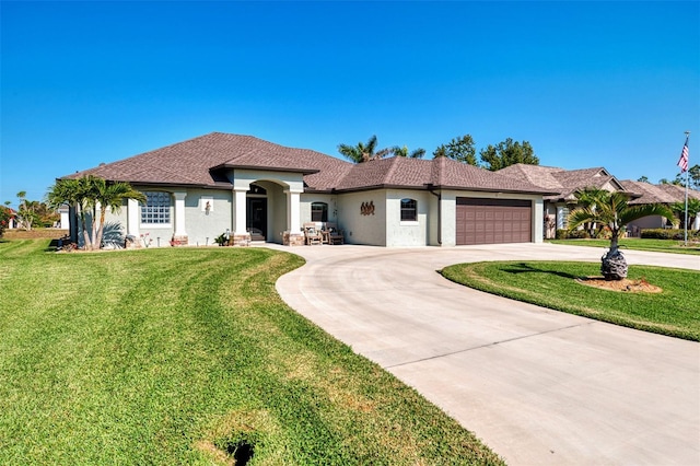 mediterranean / spanish-style home with a front lawn, curved driveway, a garage, and stucco siding