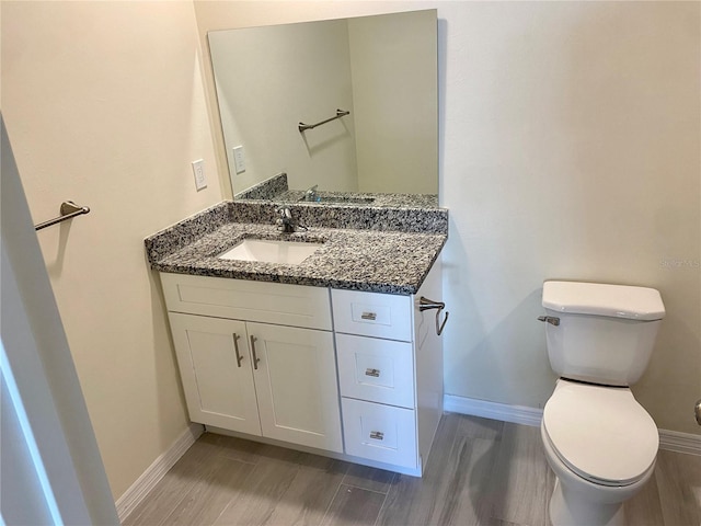 bathroom featuring vanity, toilet, baseboards, and wood finish floors