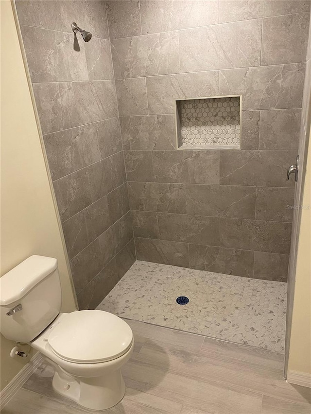 full bath with toilet and a tile shower