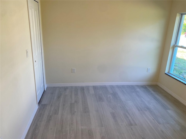 unfurnished bedroom featuring multiple windows, wood finished floors, and baseboards