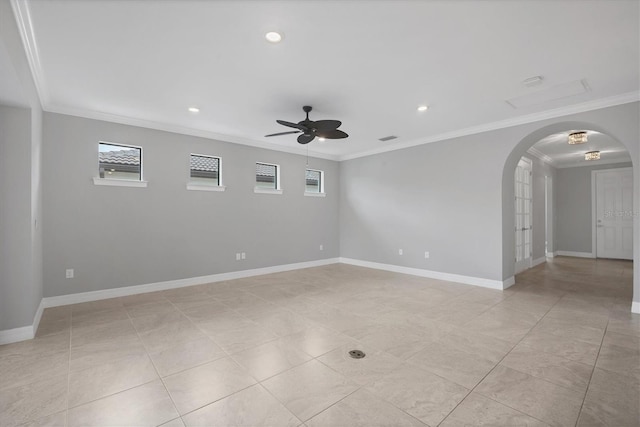 spare room with ornamental molding, baseboards, arched walkways, and ceiling fan