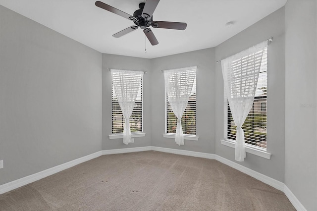 carpeted empty room with plenty of natural light, a ceiling fan, and baseboards