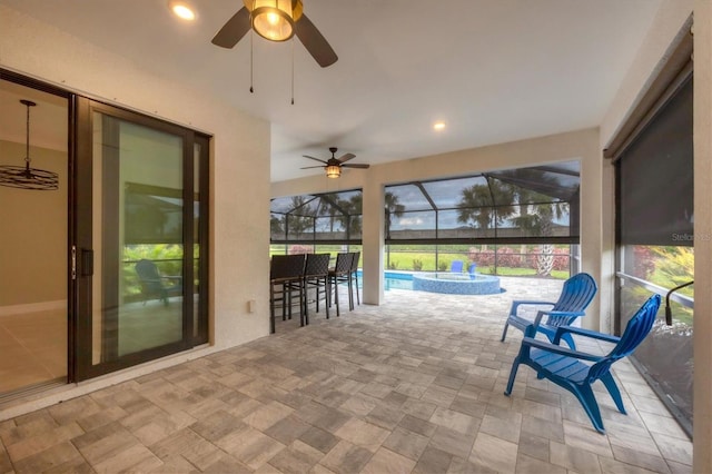 view of patio / terrace featuring a lanai, a ceiling fan, and a pool with connected hot tub