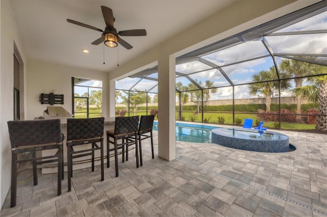 view of swimming pool featuring area for grilling, outdoor dry bar, a ceiling fan, glass enclosure, and a patio area