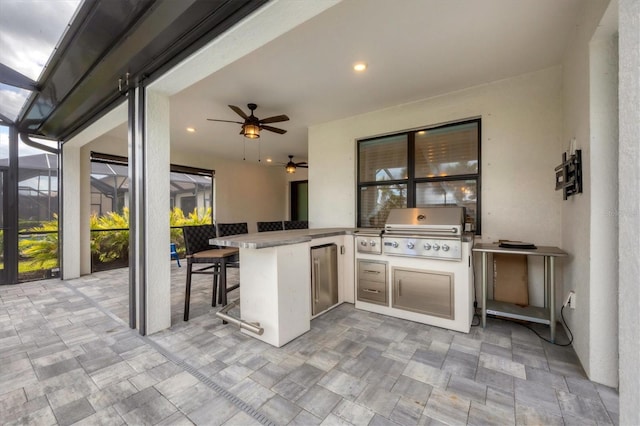 view of patio featuring grilling area, ceiling fan, exterior kitchen, glass enclosure, and outdoor wet bar