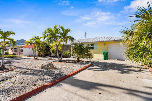 view of front of home with metal roof, concrete driveway, an attached garage, and stucco siding