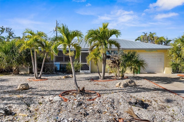 view of front of property with metal roof, driveway, an attached garage, and stucco siding