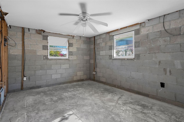 basement featuring concrete block wall and a ceiling fan