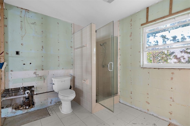 bathroom featuring tile patterned floors, toilet, tile walls, and a stall shower