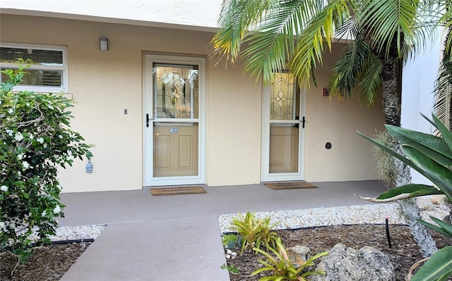 entrance to property with a porch and stucco siding