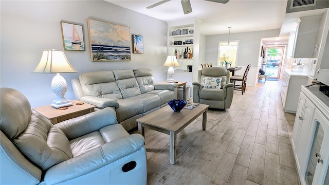 living room featuring light wood-style flooring, a ceiling fan, and visible vents