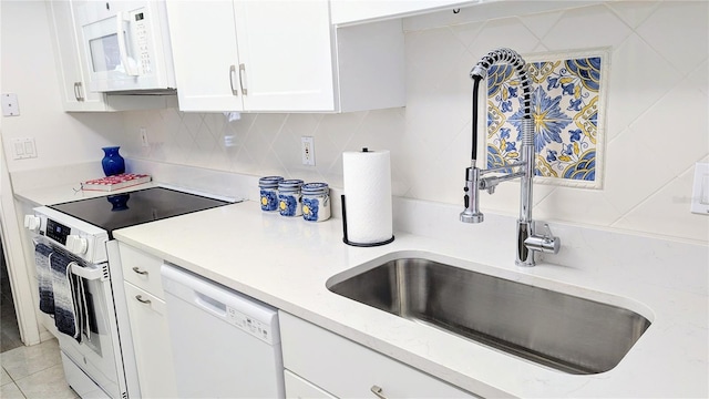 kitchen featuring white appliances, light tile patterned floors, a sink, white cabinets, and tasteful backsplash