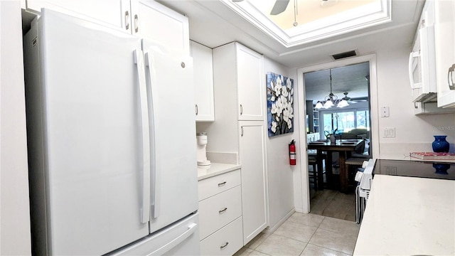 kitchen featuring white appliances, light tile patterned floors, light countertops, white cabinetry, and ceiling fan with notable chandelier