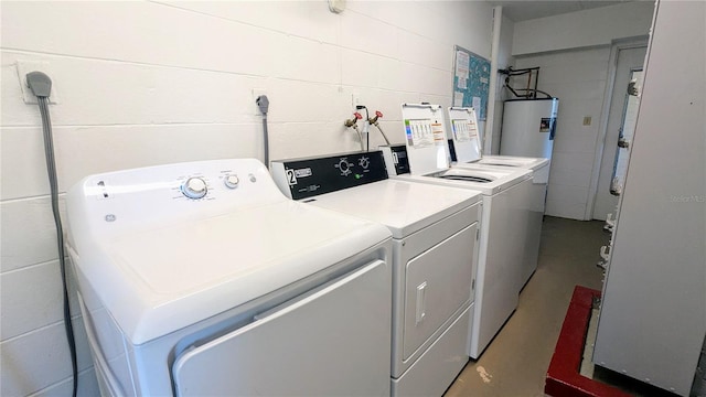 laundry room featuring washer and dryer, laundry area, concrete block wall, and electric water heater