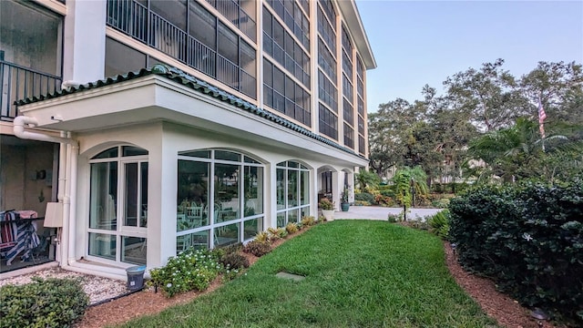 view of property exterior featuring stucco siding, a lawn, and a sunroom