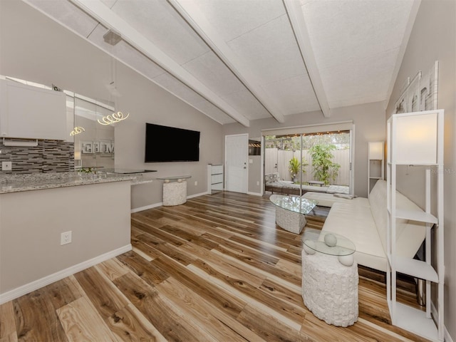 living area with lofted ceiling with beams, baseboards, and wood finished floors