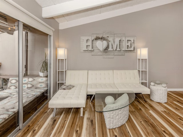 living area featuring lofted ceiling with beams, baseboards, and wood finished floors