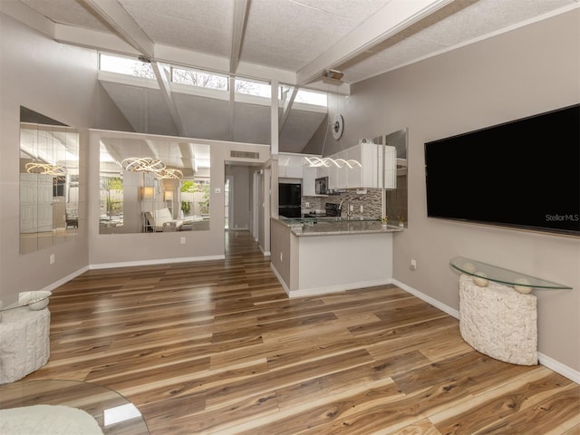 kitchen with white cabinets, lofted ceiling with beams, and wood finished floors