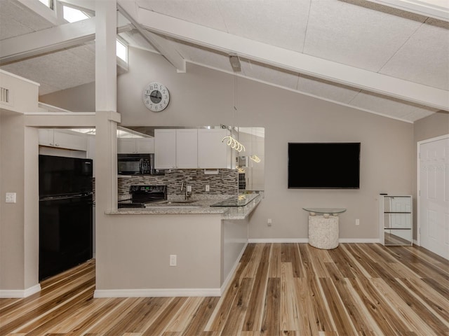 kitchen featuring light wood finished floors, decorative backsplash, black appliances, and lofted ceiling with beams