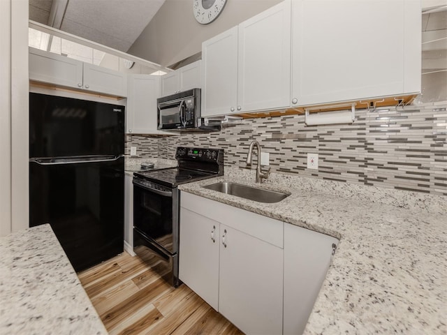 kitchen with light wood-style flooring, a sink, black appliances, white cabinetry, and backsplash