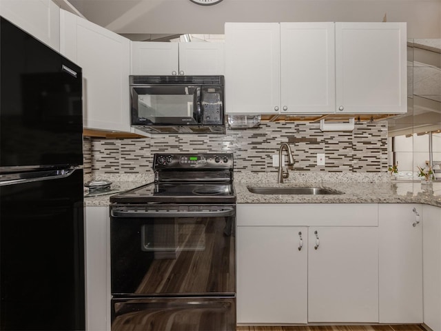 kitchen with black appliances, white cabinets, tasteful backsplash, and a sink