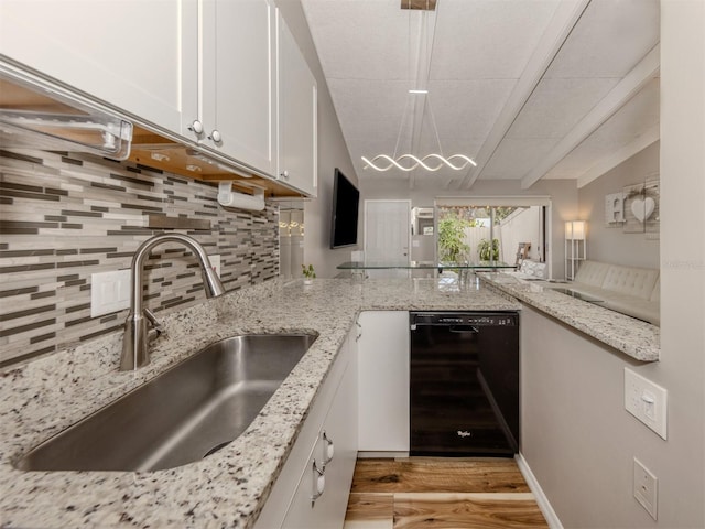 kitchen with tasteful backsplash, a chandelier, black dishwasher, white cabinetry, and a sink