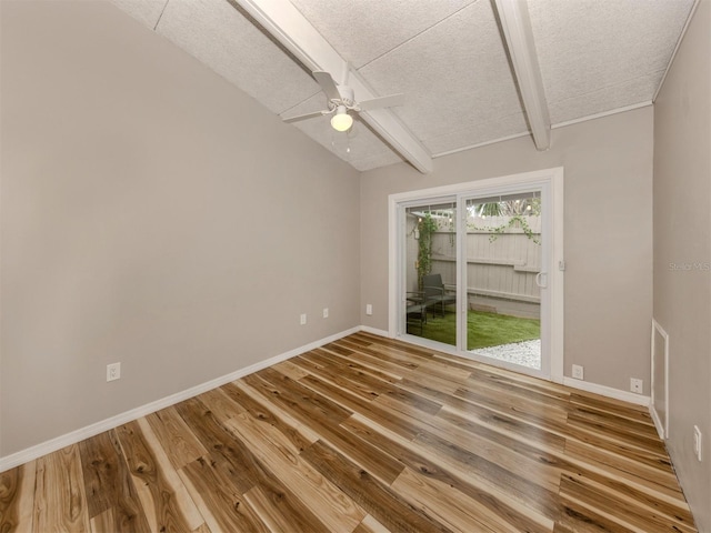 empty room featuring lofted ceiling with beams, wood finished floors, and baseboards