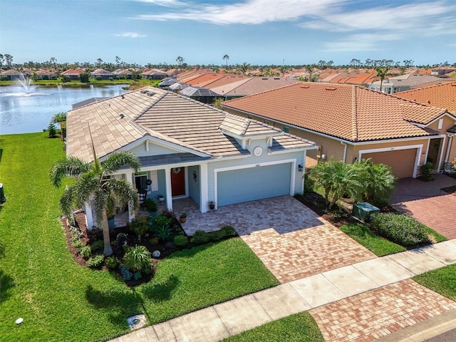 view of front of home with a tiled roof, a water view, decorative driveway, a front yard, and a garage