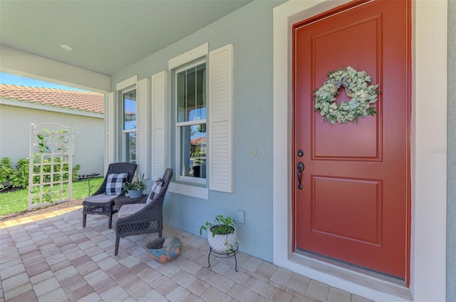 entrance to property featuring covered porch and stucco siding