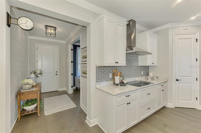 kitchen featuring black electric cooktop, ornamental molding, and wall chimney exhaust hood
